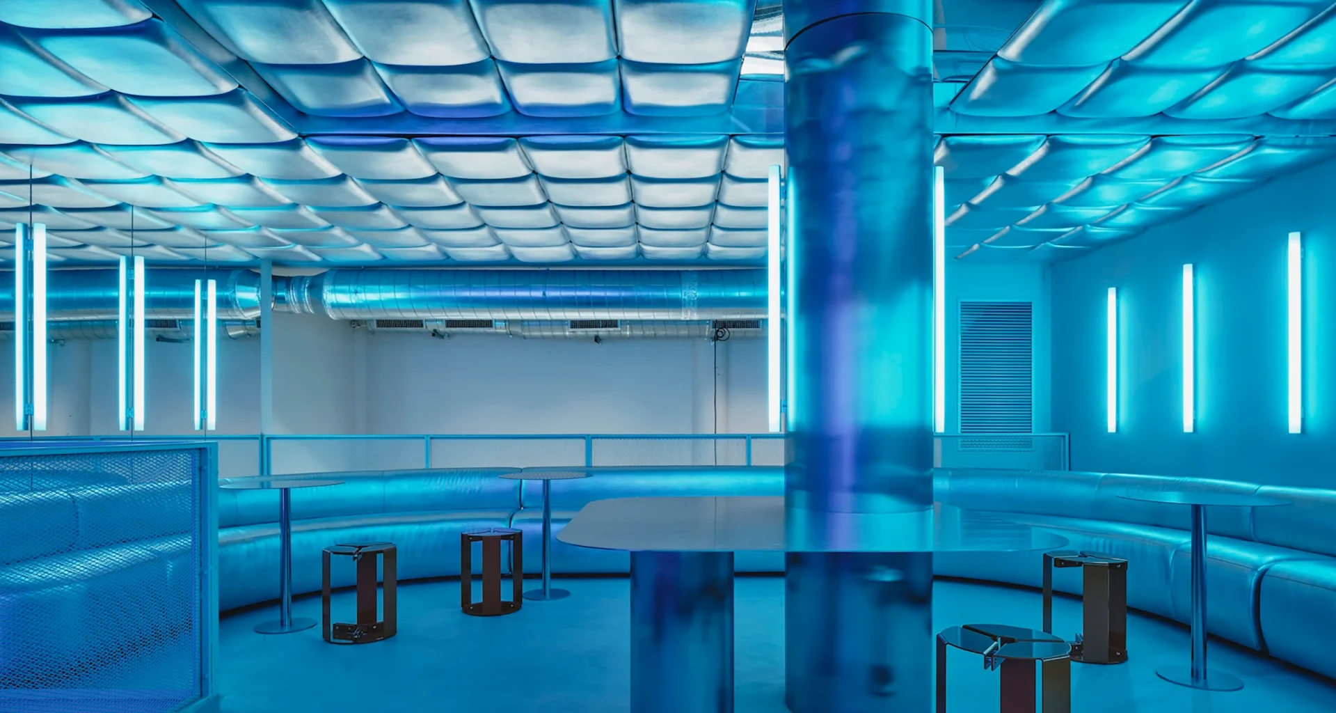 Isern Serra Relleno Barcelona interior design featuring metallic padded walls, stainless steel tables, and blue RGB lighting tint.