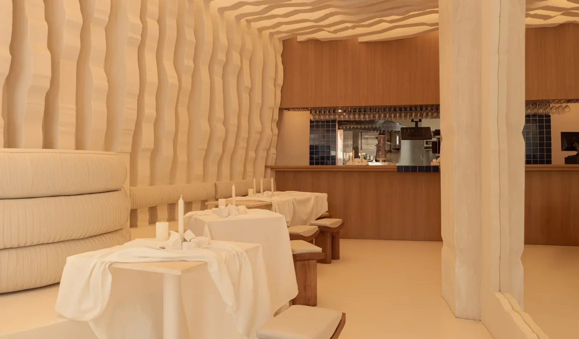 Masquespacio Egeo souvlaki Madrid interior showing monolithic beige microcement walls, custom seating, and broken Greek architectural column with integrated light.