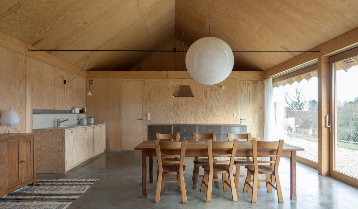 Un Maison en Normandie kitchen dining area by exercice and Anna Le Régent, showcasing structural timber and the double-height void.