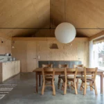 Un Maison en Normandie kitchen dining area by exercice and Anna Le Régent, showcasing structural timber and the double-height void.