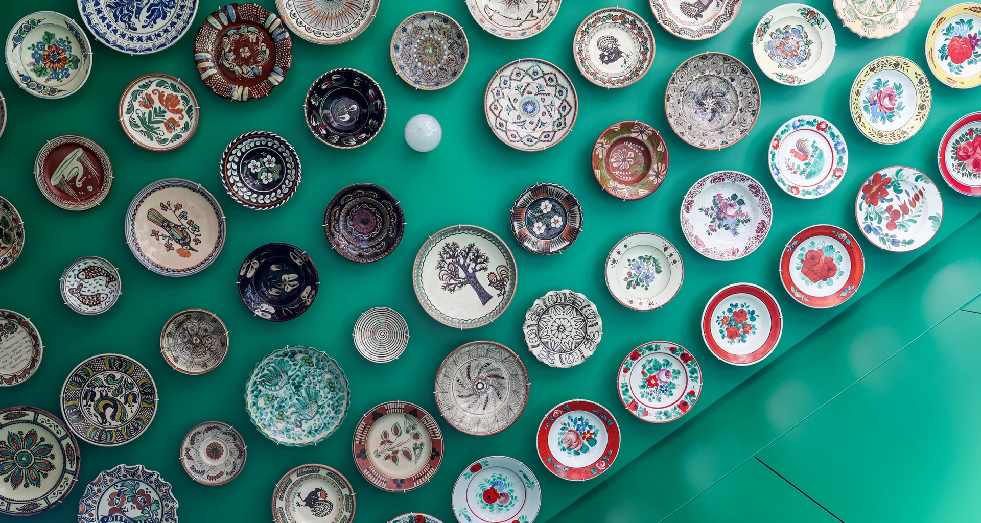 Tine Loncin designed deep green kitchen in Brussels apartment, blending Romanian folk art with contemporary design.