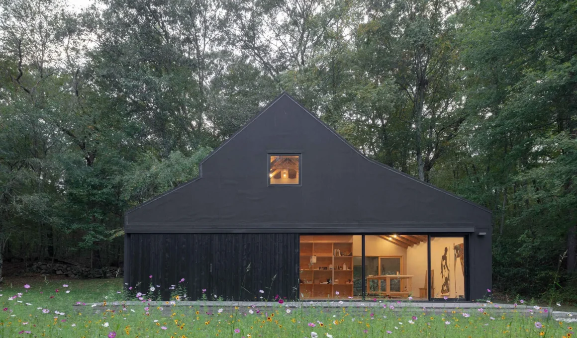 Worrell Yeung Studio Barn exterior view, clad in black asphalt roofing material, featuring a large 17-foot glazed opening and sliding shutter barn door.