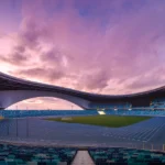 Zaha Hadid Guangzhou Stadium interior showing massive curved arch opening over 60,000-seat field