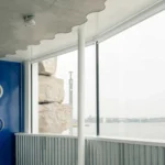 Bureau-designed Phare Ylliam lighthouse in Geneva, Switzerland. The ultra-light hyperboloid structure stands on a rocky base by Lake Geneva.