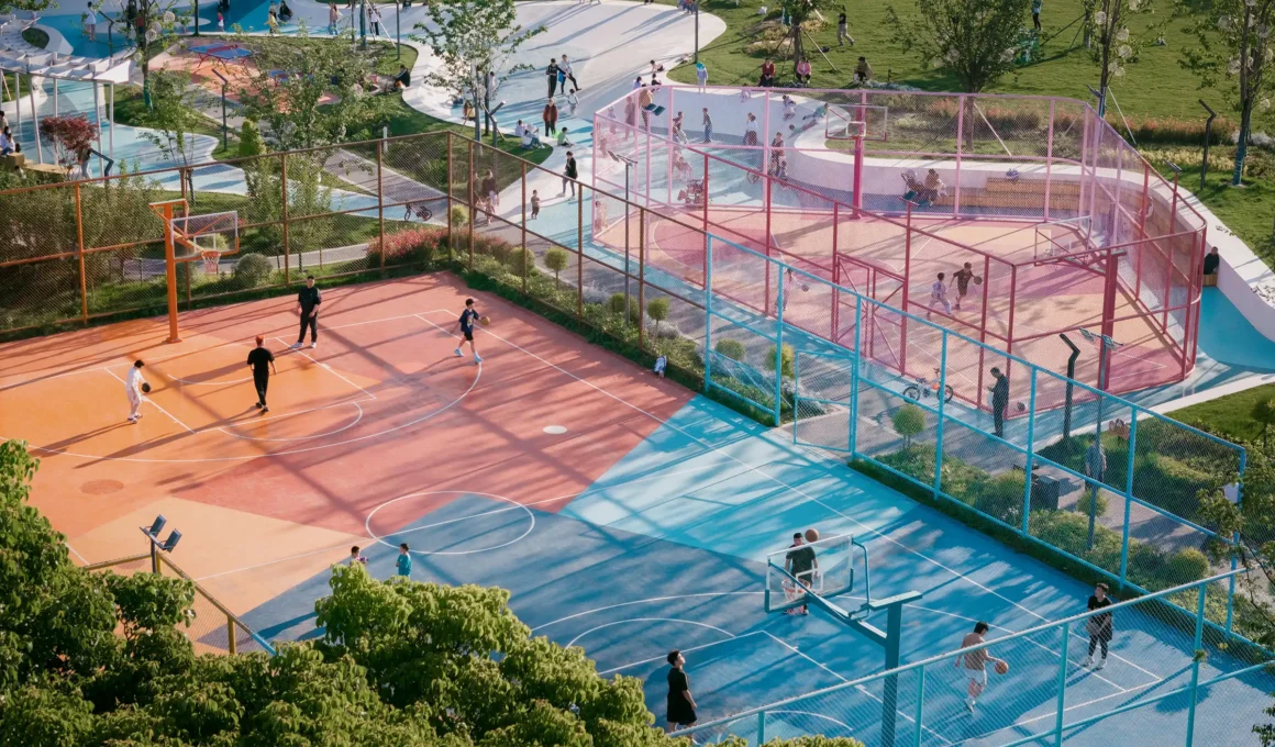 Aerial view of SoBA's Vibrant Sports Park in Suzhou, showing blue and pink basketball courts contrasting with the white UHPC flowing skate ribbon inspired by Kunqu opera.