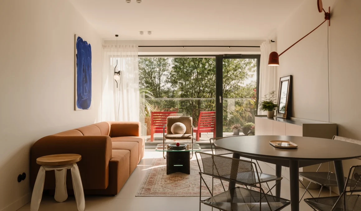 one desk designed minimalist living room in Krakow apartment featuring microcement floor, rust sofa, and view of Vistula River valley.