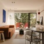 one desk designed minimalist living room in Krakow apartment featuring microcement floor, rust sofa, and view of Vistula River valley.