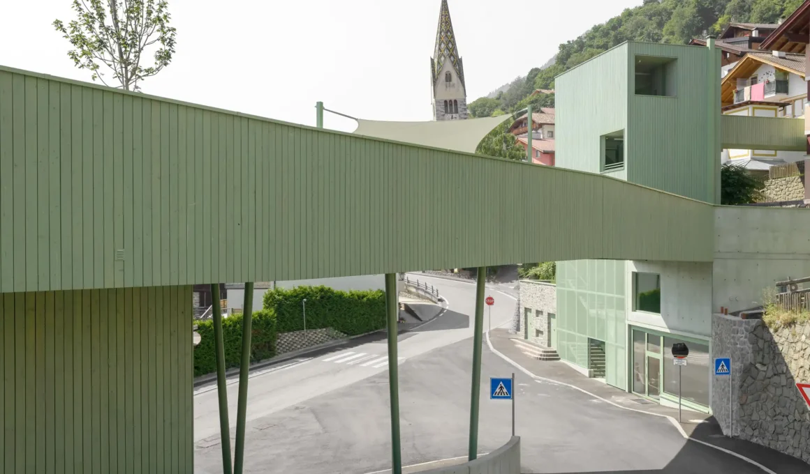 Roland Baldi Architects’ multifunctional green bridge ensemble aerial view in Barbiano, South Tyrol, featuring sustainable architecture and integrated kindergarten.