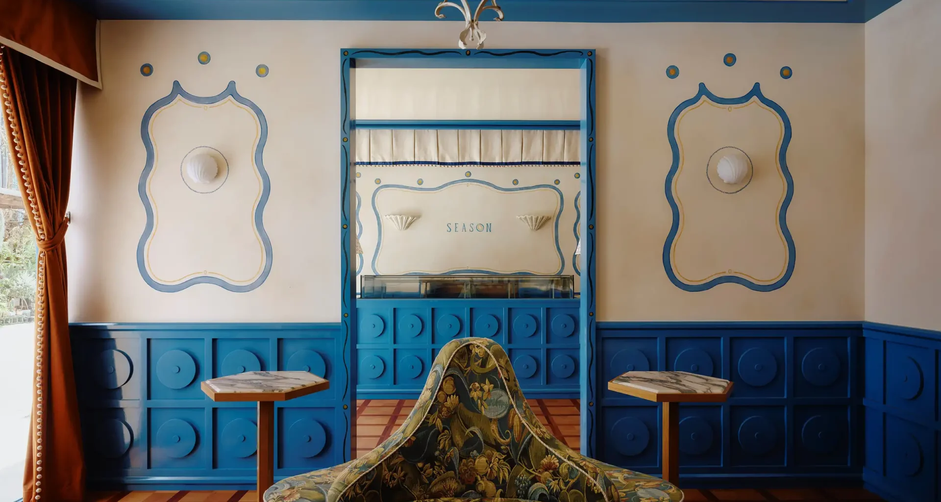 Floral upholstered armchair set against blue and ivory wainscoting with "SEASON" branding at Season Patisserie in Taipei by ECRU STUDIO.