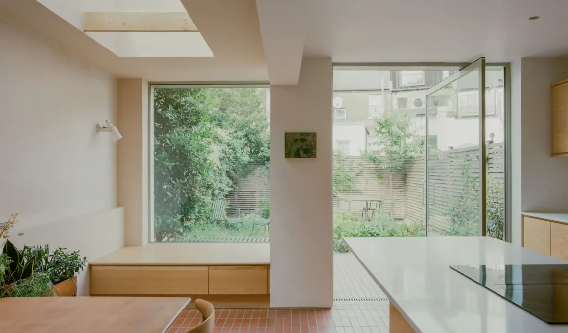Type Studio Denmark Hill Victorian terrace extension with frameless corner window, brick, and garden view.