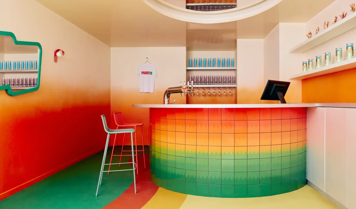 Uchronia Padel 15 indoor court bar design in Paris, featuring a chromatic tiled counter with a green-to-orange gradient and vibrant burnt orange walls.