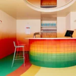 Uchronia Padel 15 indoor court bar design in Paris, featuring a chromatic tiled counter with a green-to-orange gradient and vibrant burnt orange walls.