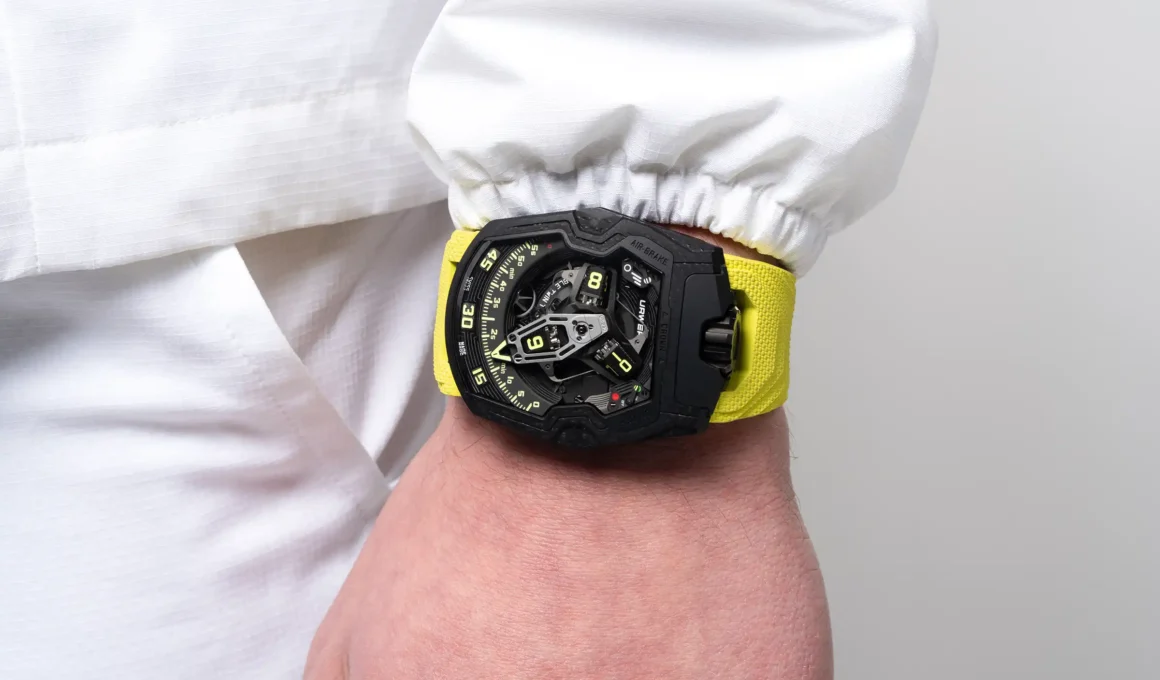 URWERK UR-230 Black Star watch with yellow vulcanized rubber strap showing wandering hours complication and black ceramic composite case.
