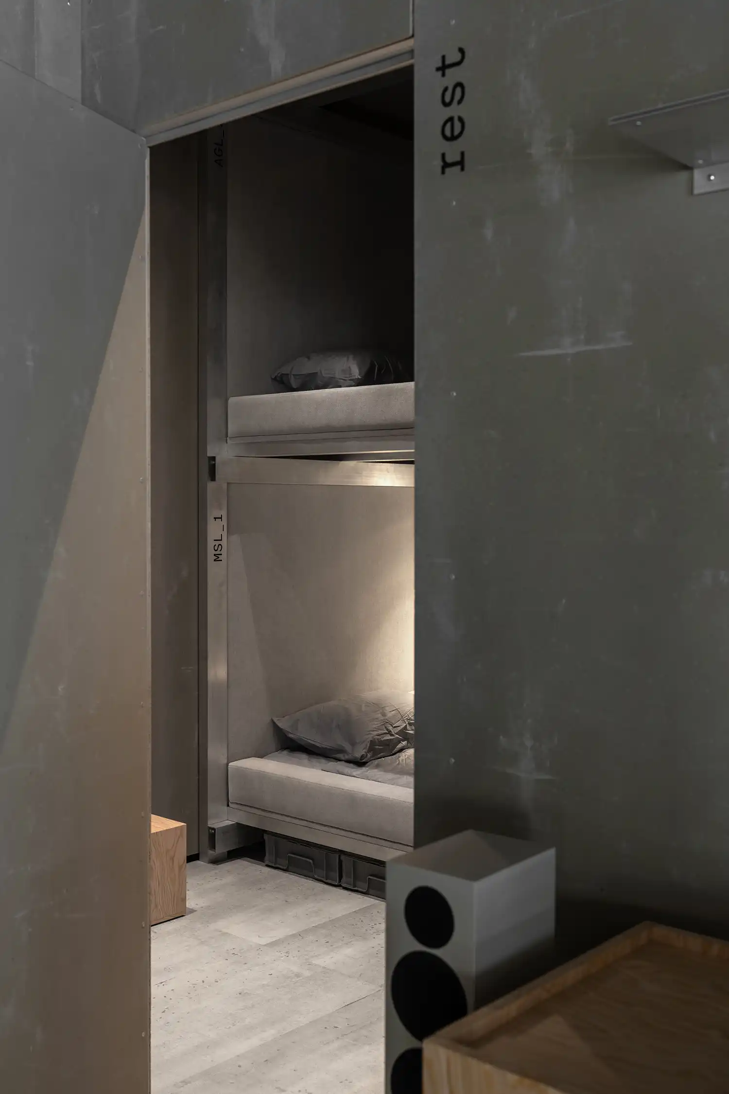 Minimalist sleeping area with built-in metal bunk beds and upholstered acoustic fabric panels.