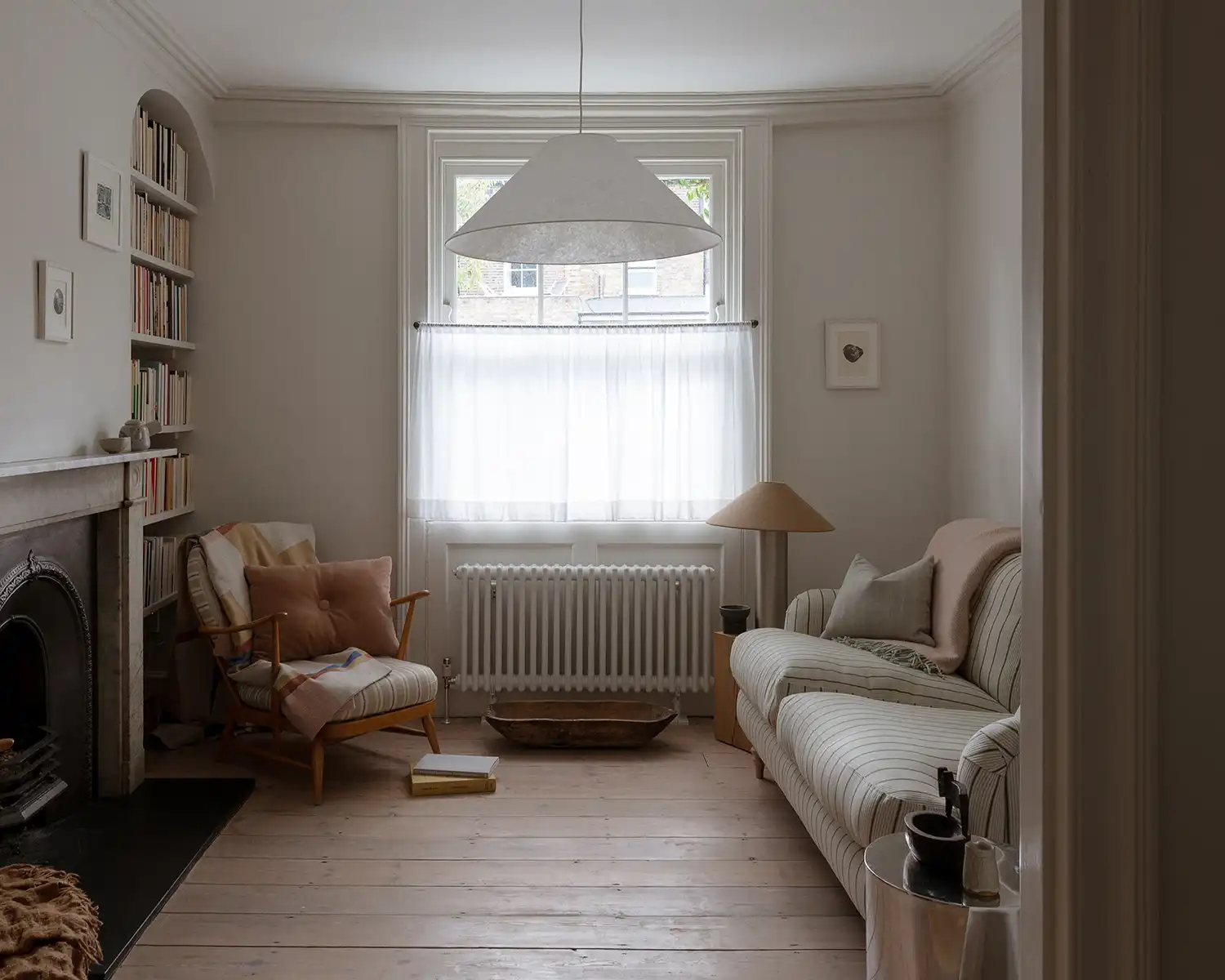 A luminous Georgian reception room with white-soaped pine floorboards and a central paper globe pendant.