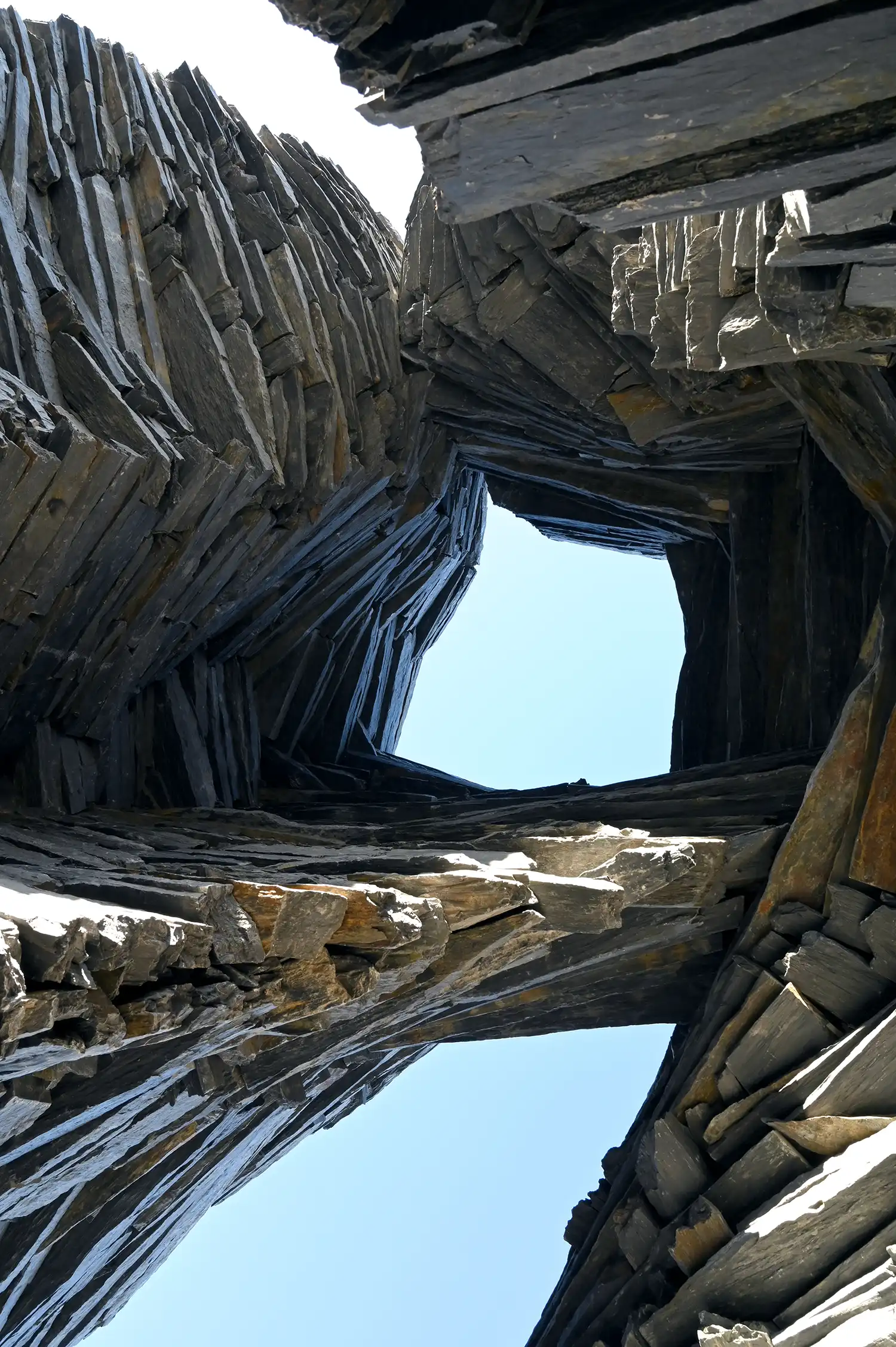 Close-up of dark, weathered stone layers with rough edges and grey-black tones.