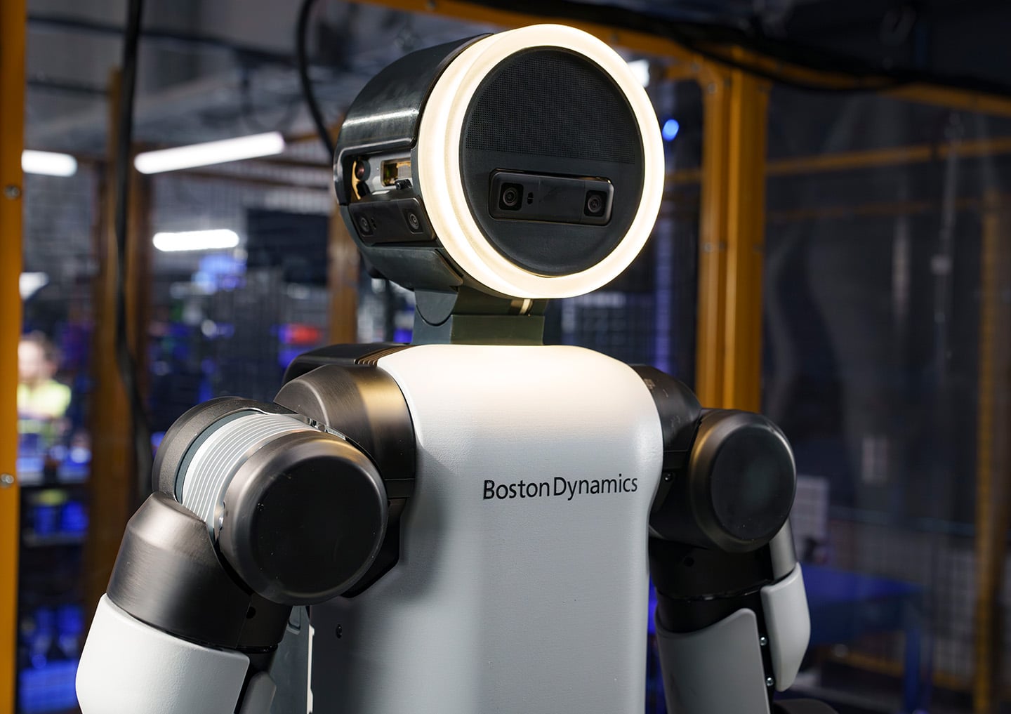 A detailed portrait of the Atlas robot’s head, showing dual optical sensors encased in a distinctive glowing halo ring.