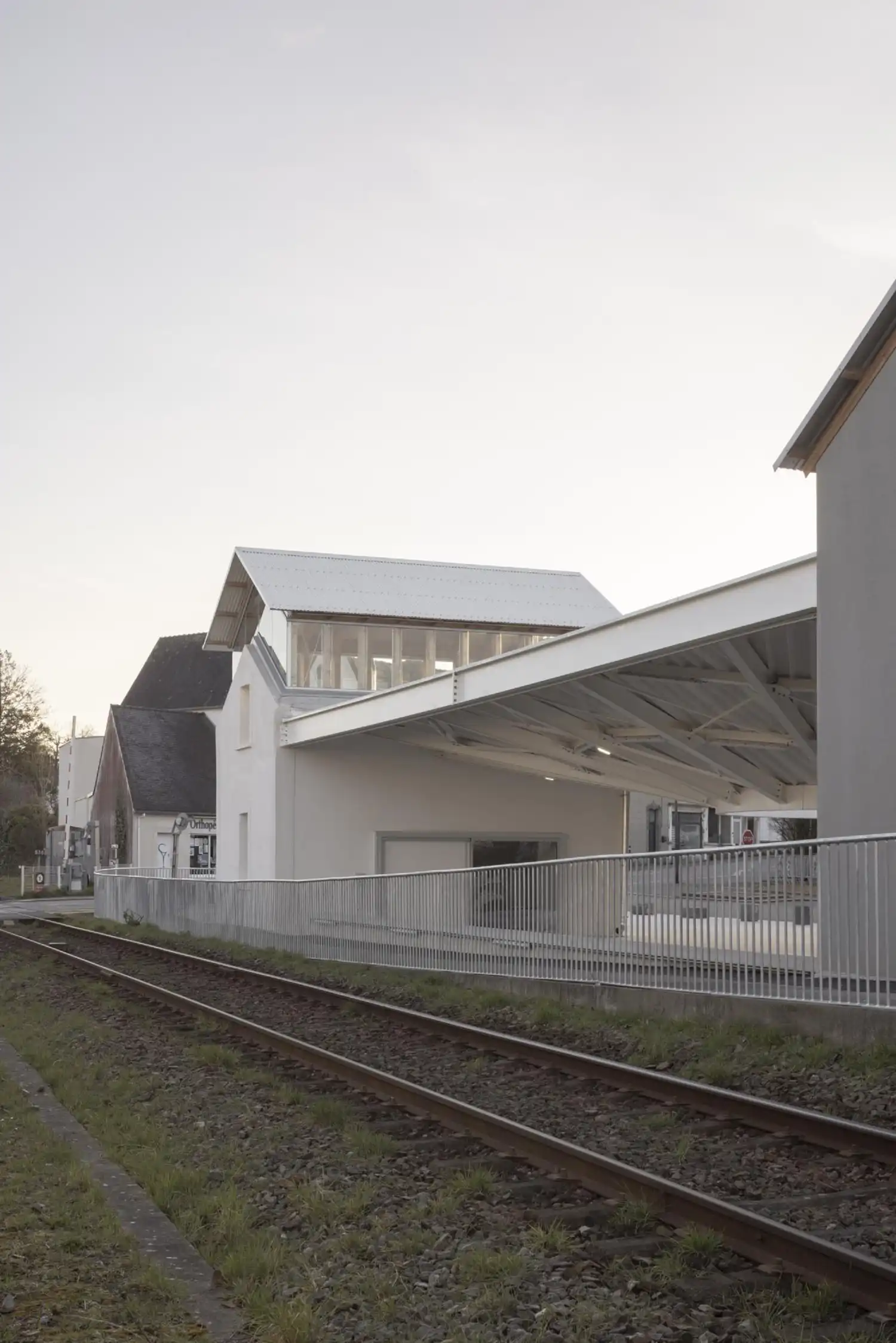 Side profile of the renovated station pavilion with a new glazed upper level and attached modern canopy.