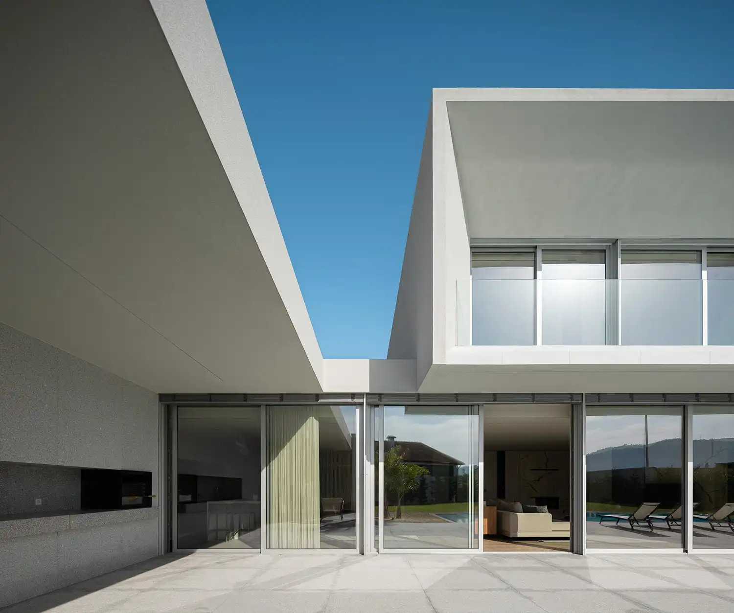 Minimalist patio and pool area of Casa Branca with large glass sliding doors.