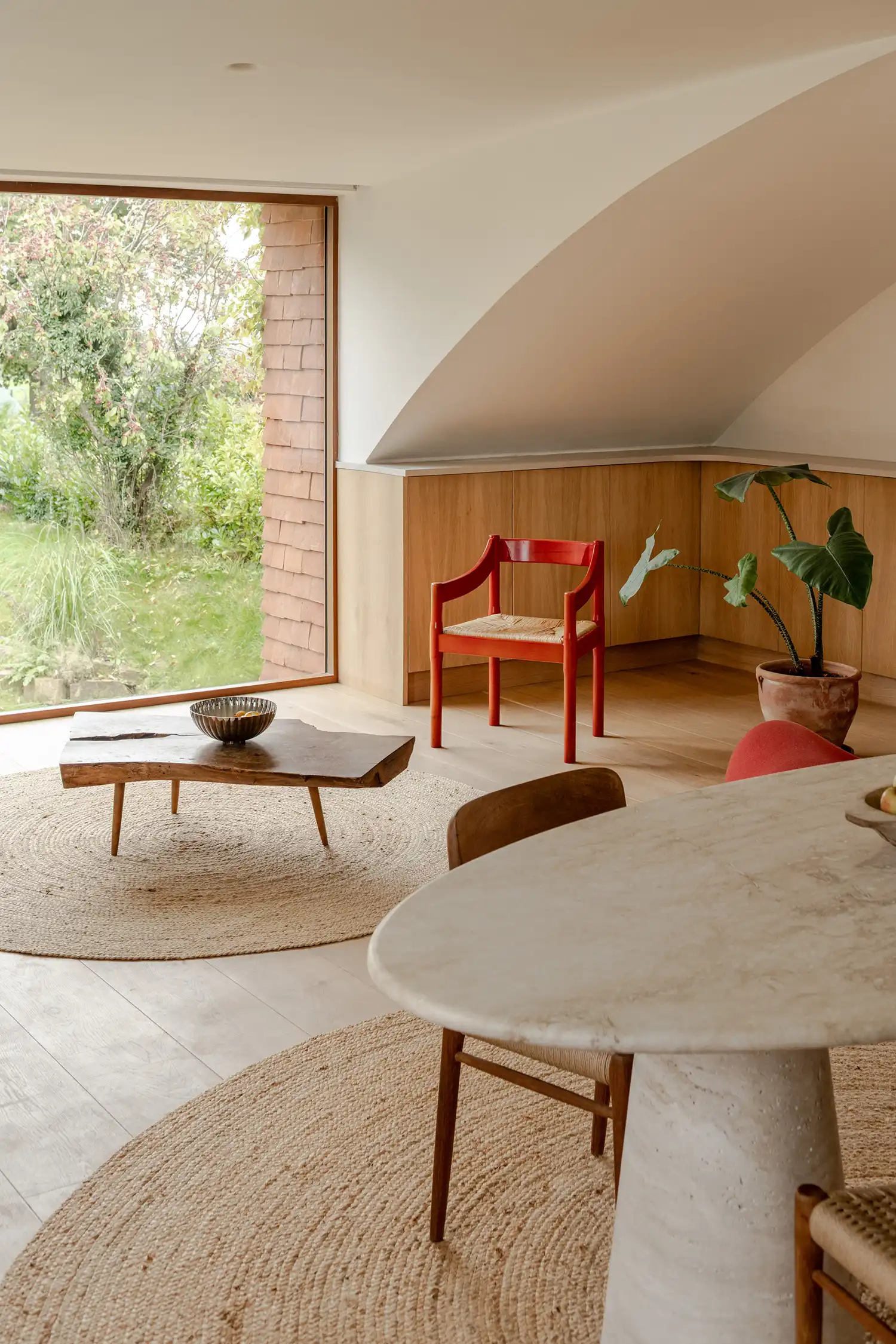 Living space with curved ceiling, large window, and mid-century modern furniture