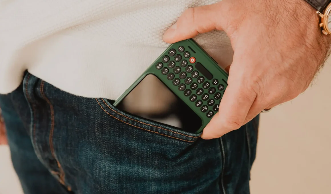 Clicks Technology Communicator green smartphone in a denim pocket.