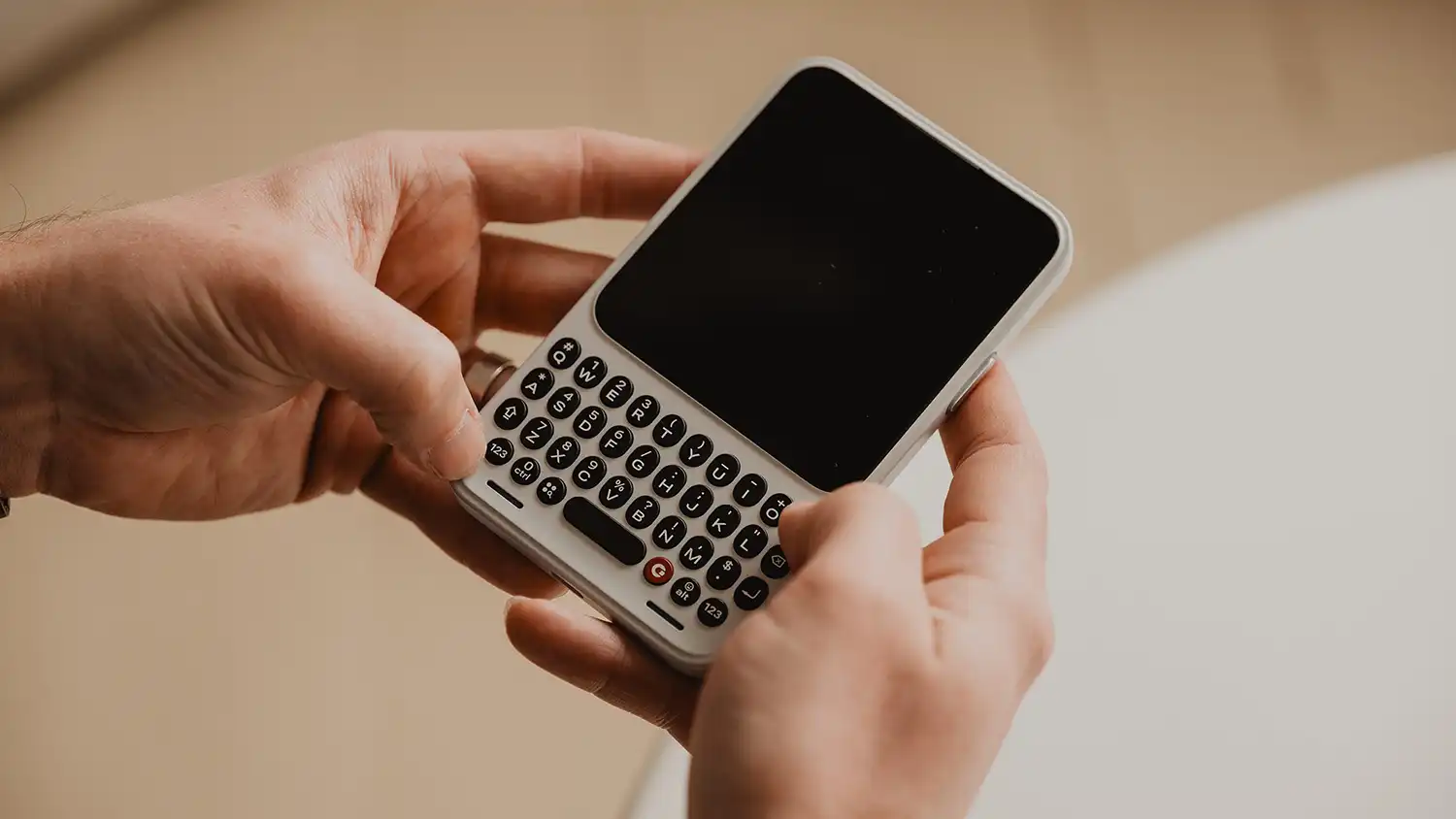 Hands typing on a white Clicks Communicator tactile keyboard.