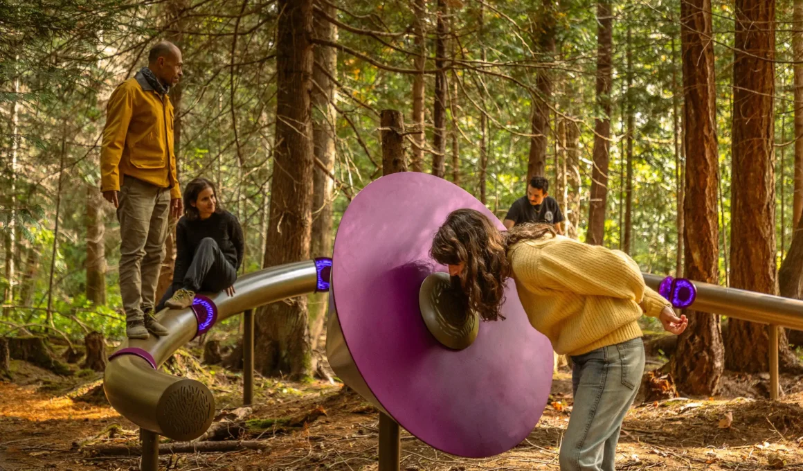 A woman vocalizing into a purple acoustic dish in a British Columbia forest.