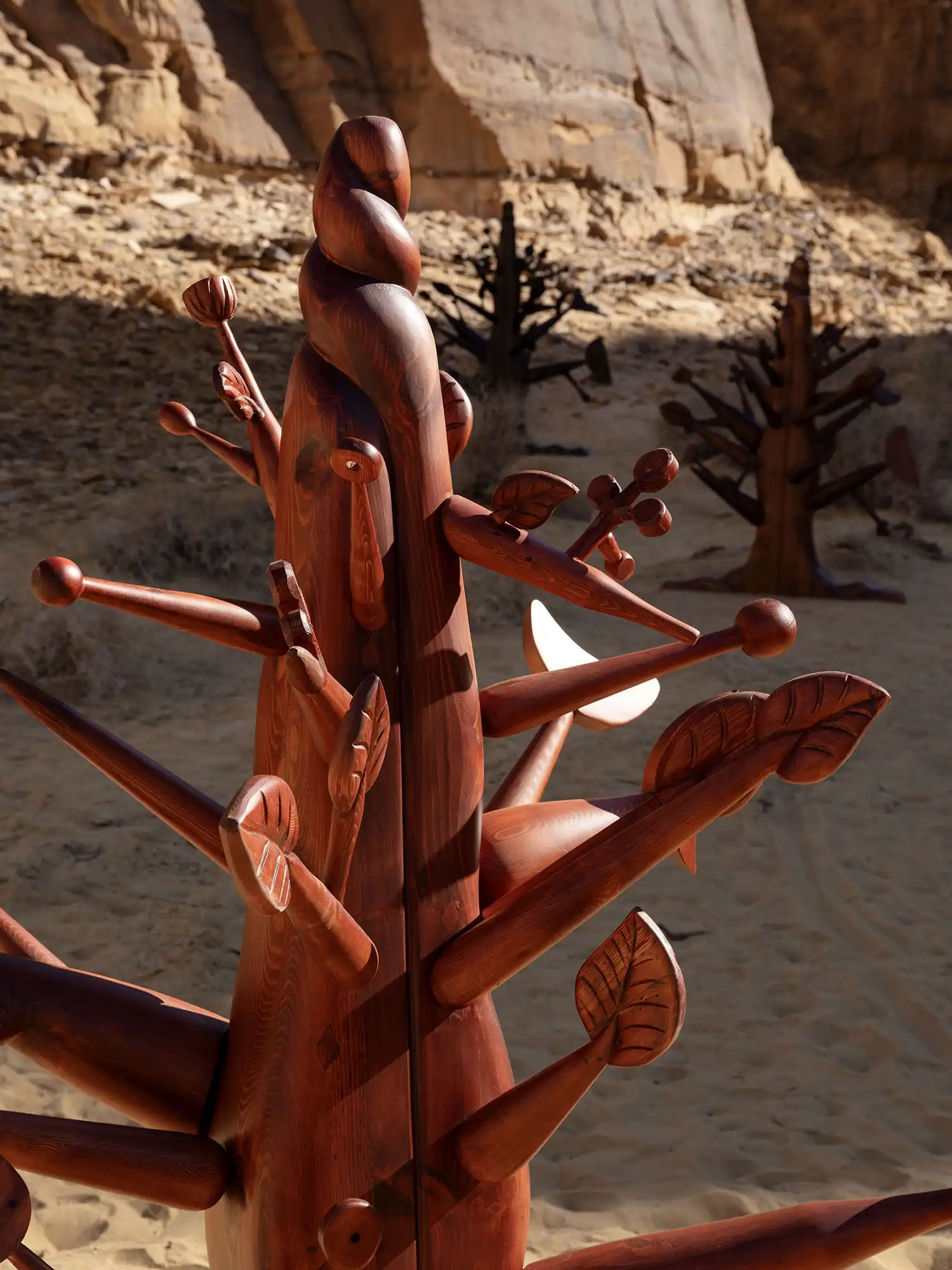 Close-up of a carved wooden sculpture by Ibrahim El-Salahi resembling a tree with multiple branches and leaf details.