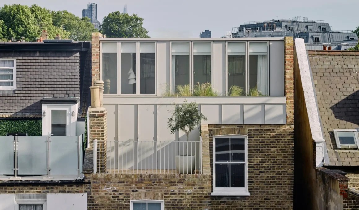 Exterior view of a London terrace house with a modern grey metal roof extension and a small balcony.