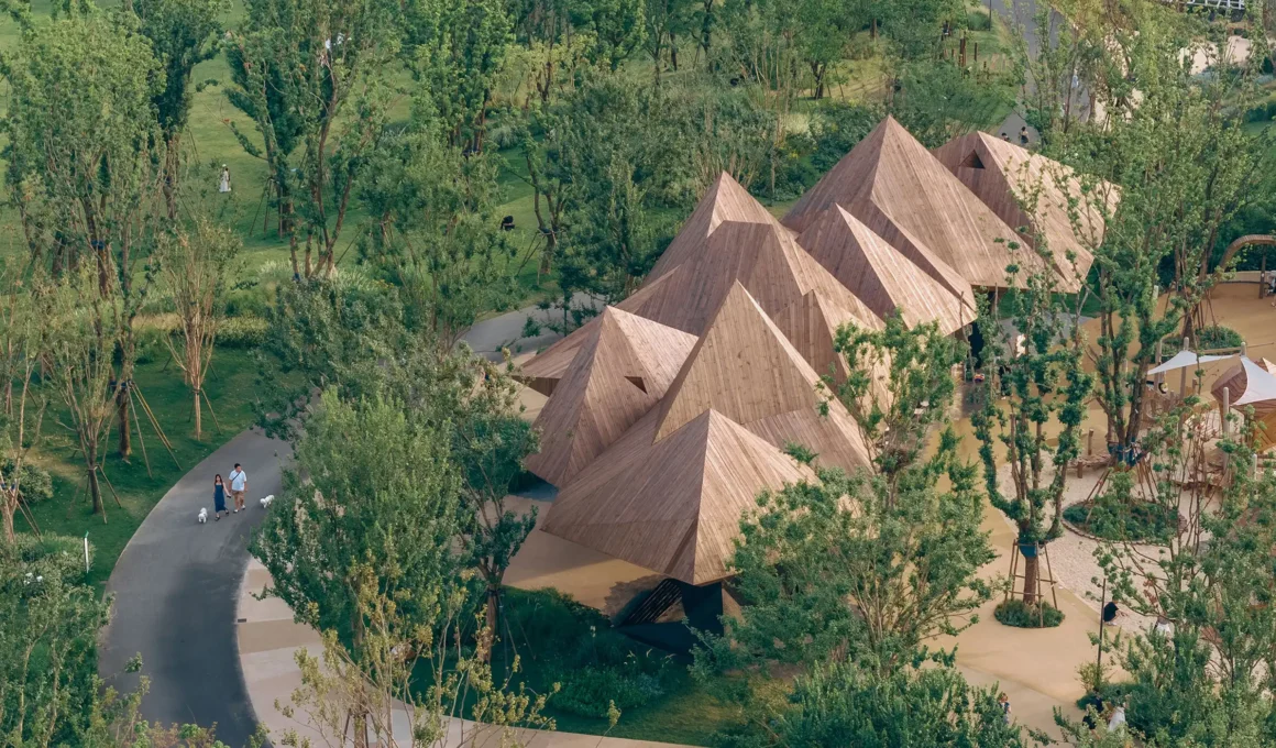 Aerial view of The Dancing Mountain restaurant in Wuhan, featuring a rhythmic series of faceted solid wood pyramids cantilevered over a lush park landscape.