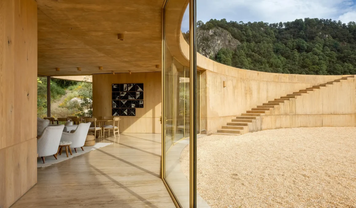 View from inside a wood-paneled living space looking out toward a curved courtyard with stone stairs.