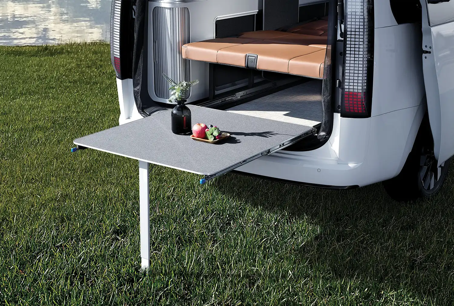 Detail of the pull-out exterior table extending from the rear of the STARIA Camper.