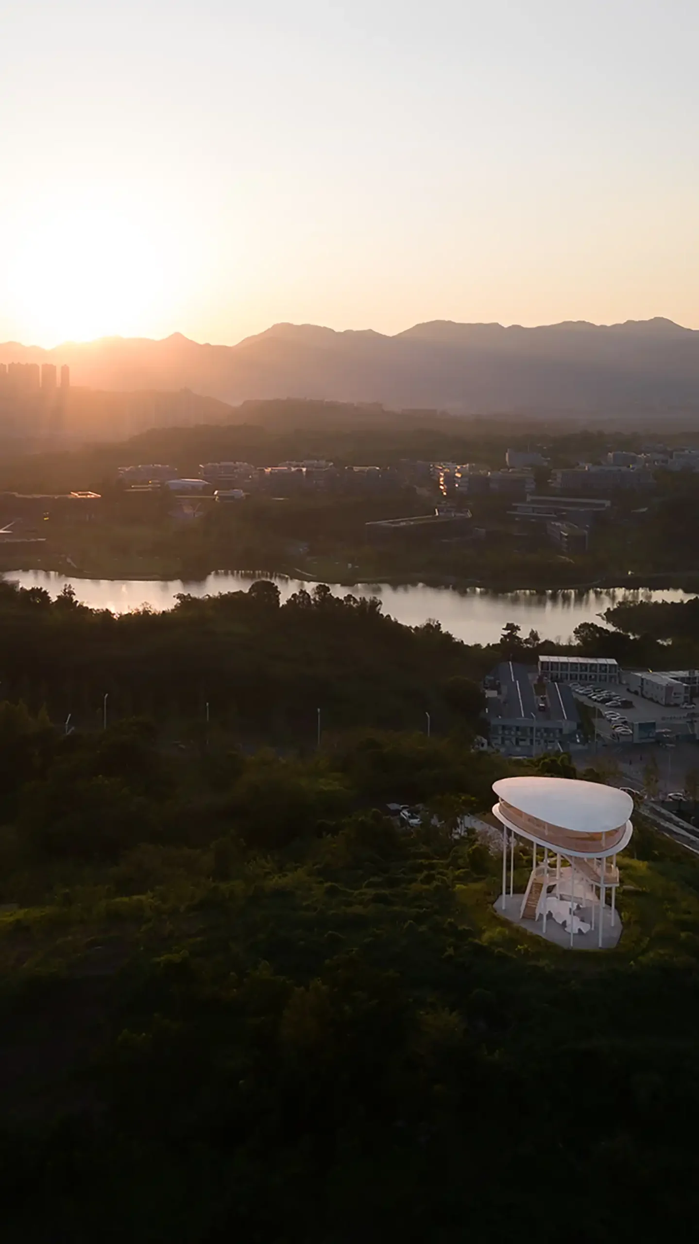 Aerial view of gad's Landscape Tower in the Liangjiang Synergy Innovation Zone overlooking the city and lake at dusk.
