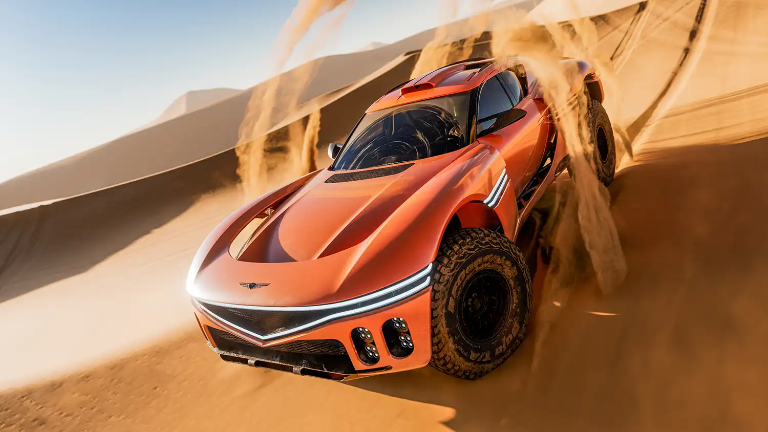 Front view of an orange Genesis X Skorpio Concept navigating a sand dune.