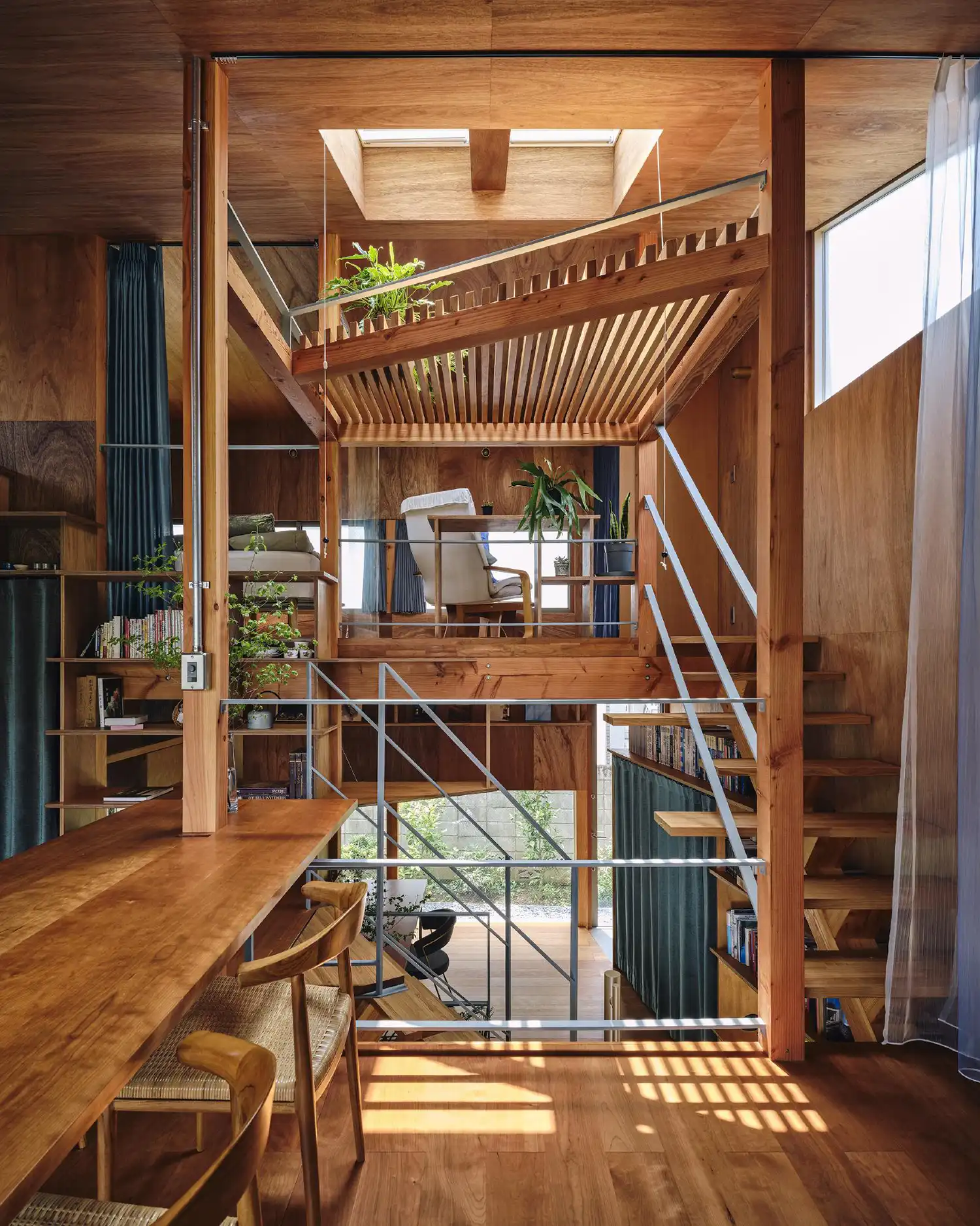 A complex split-level interior view of a wooden house in Tokyo, showing multiple floors, stairs, and a skylight.