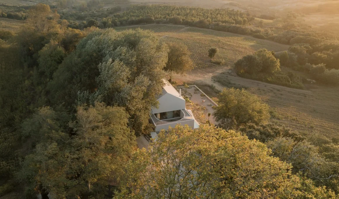 Aerial view of a minimalist white house with a semi-circular patio designed by Atelier Matteo Arnone, nestled within the historic vineyards of Alenquer, Portugal.