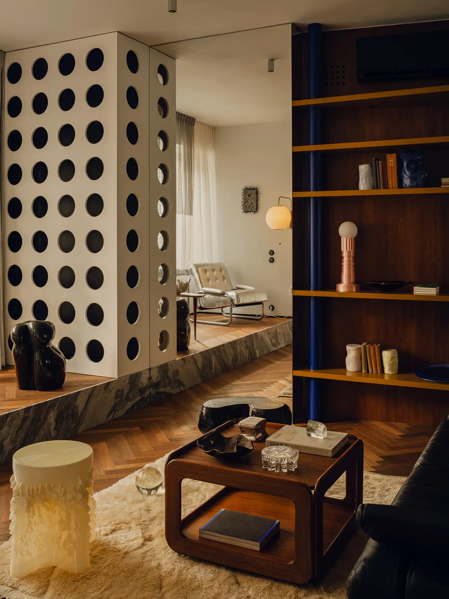 Living room detail featuring a white perforated room divider and wooden coffee table.