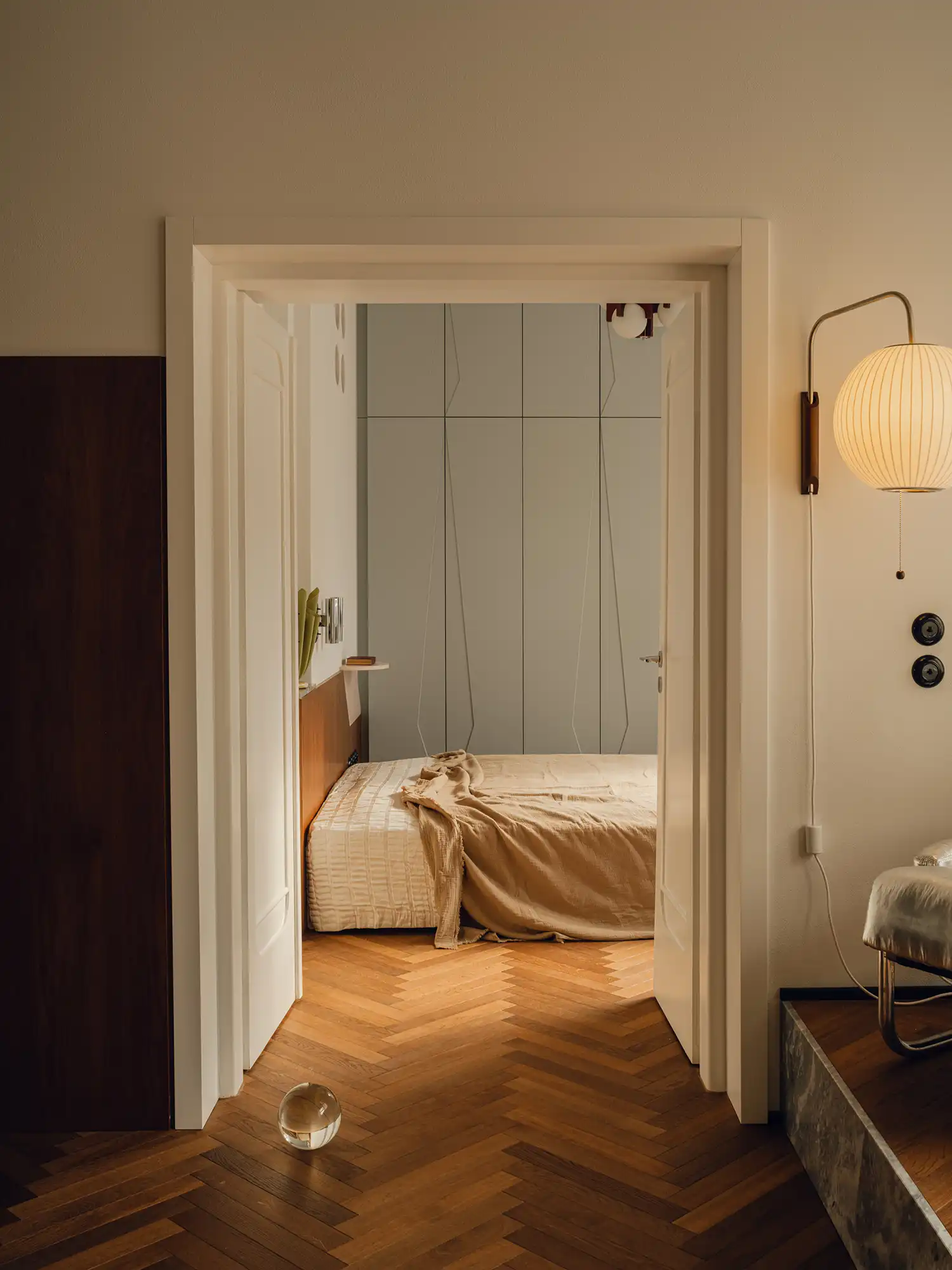 View into a bedroom with a low bed and light gray wardrobes with geometric lines.