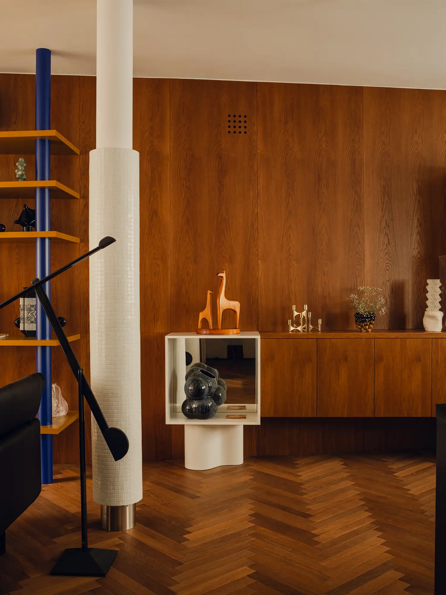 Close-up of a white tiled column next to a blue shelf and warm wood-paneled walls.