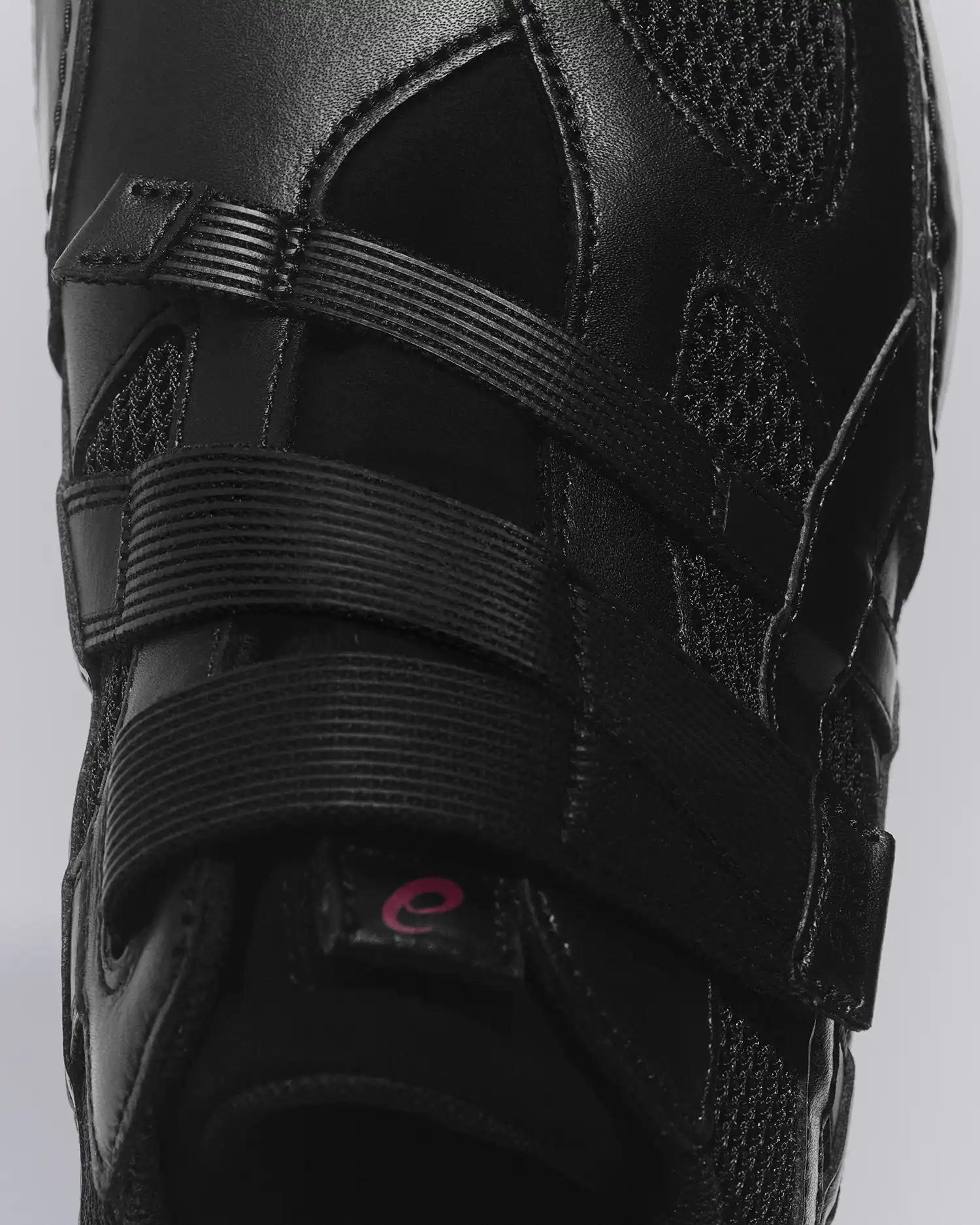 A close-up of the all-black HYPER TAPING™ model emphasizing the play between matte leather, gloss finishes, and technical mesh.