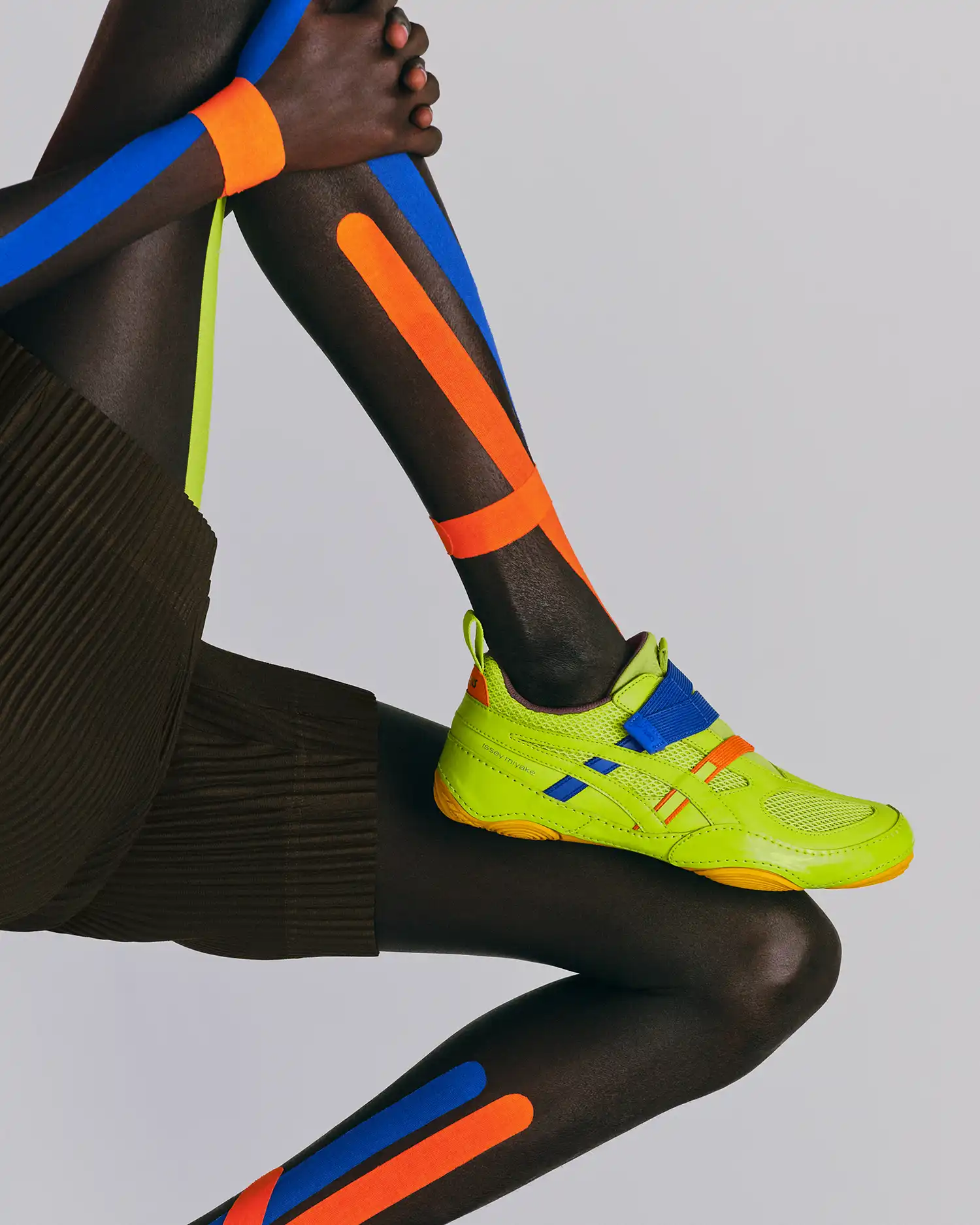 A model wearing the fluorescent green HYPER TAPING™ sneaker with matching athletic taping applied to the leg.