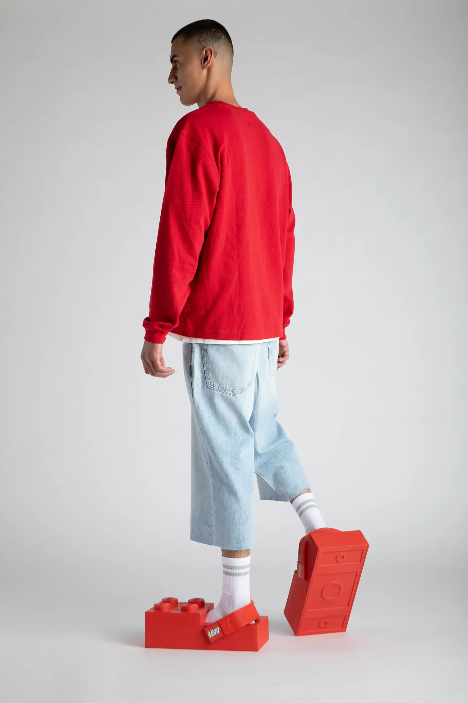 A person walking in red LEGO Brick Clogs, showing the rectangular brick-patterned tread on the outsole.