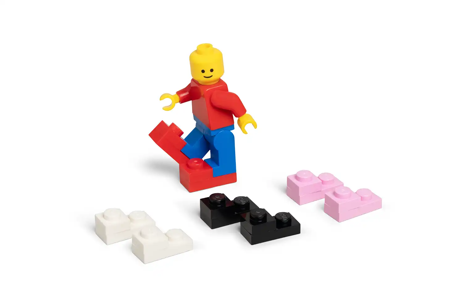 A LEGO Minifigure standing next to four pairs of miniature Crocs in red, white, black, and pink.