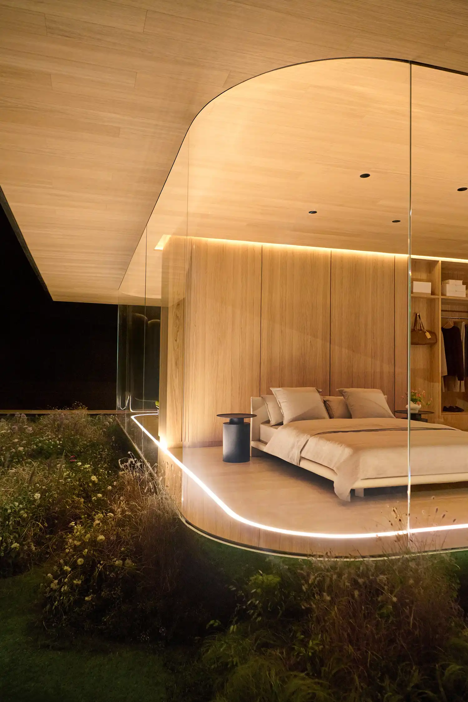 Close-up of the DROPHAUS glass corner showing a minimalist bedroom with wood paneling.