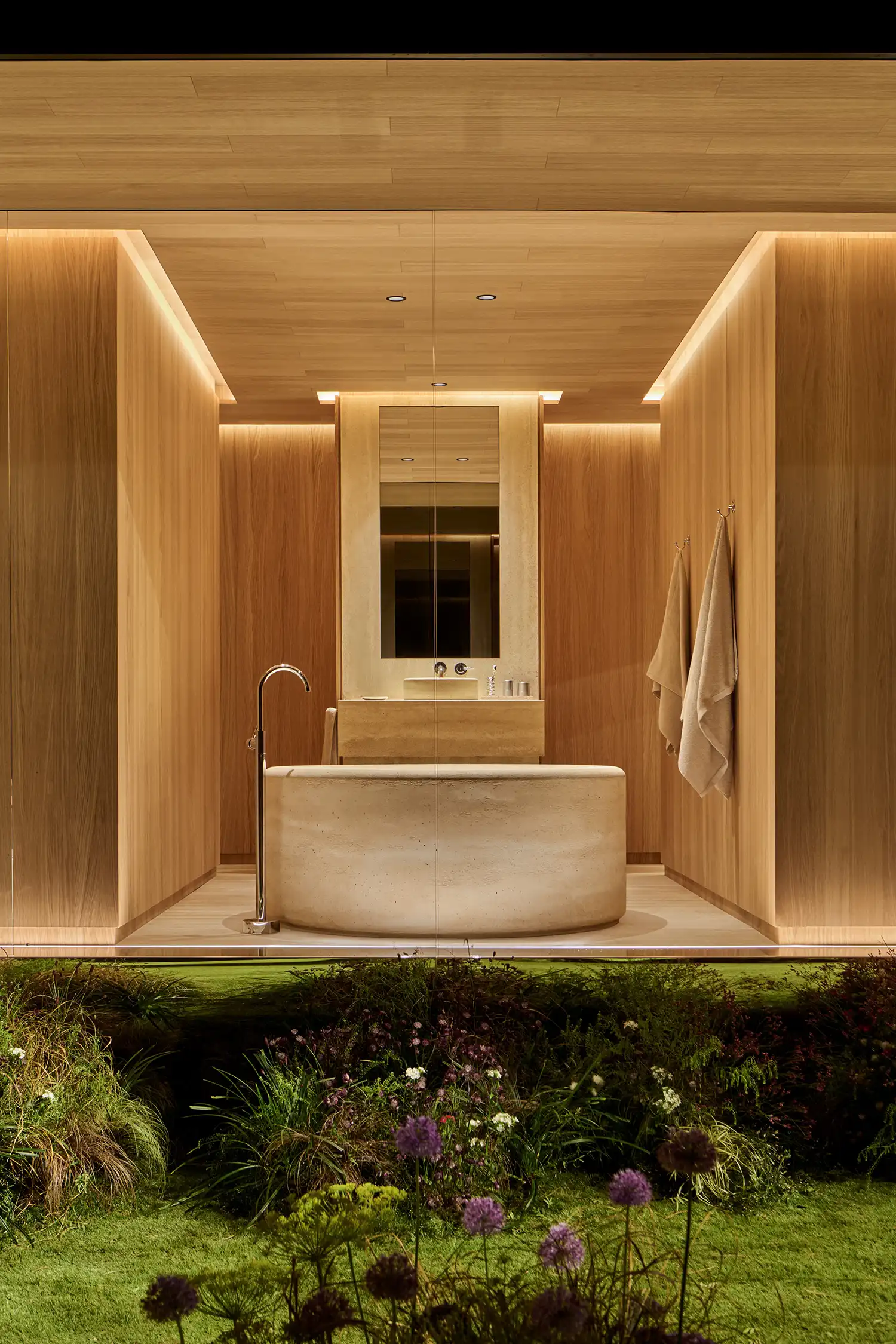 Minimalist bathroom interior in the DROPHAUS featuring a stone bathtub and wooden walls.