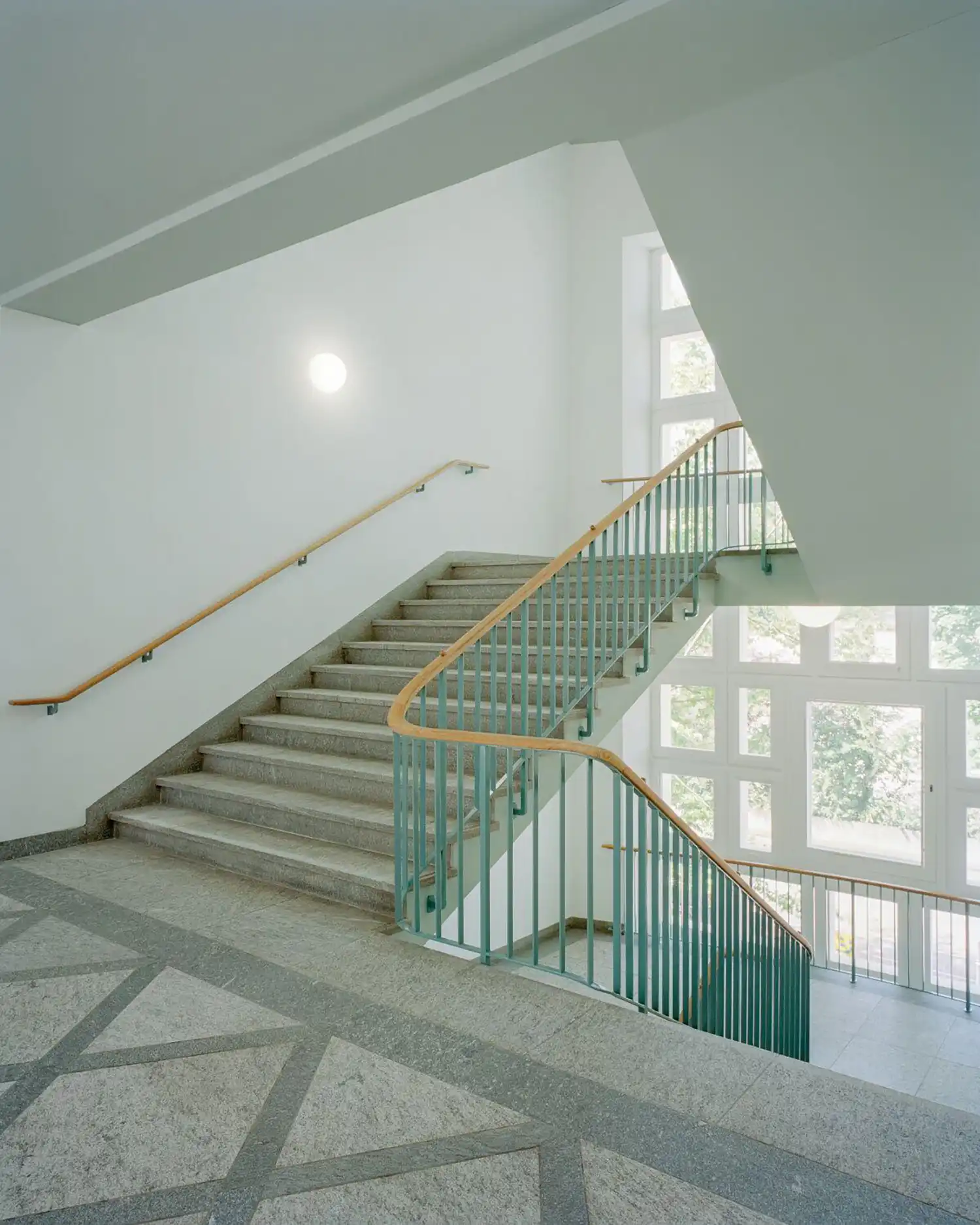 Modernist staircase with mint green railings and terrazzo flooring in Basel school.