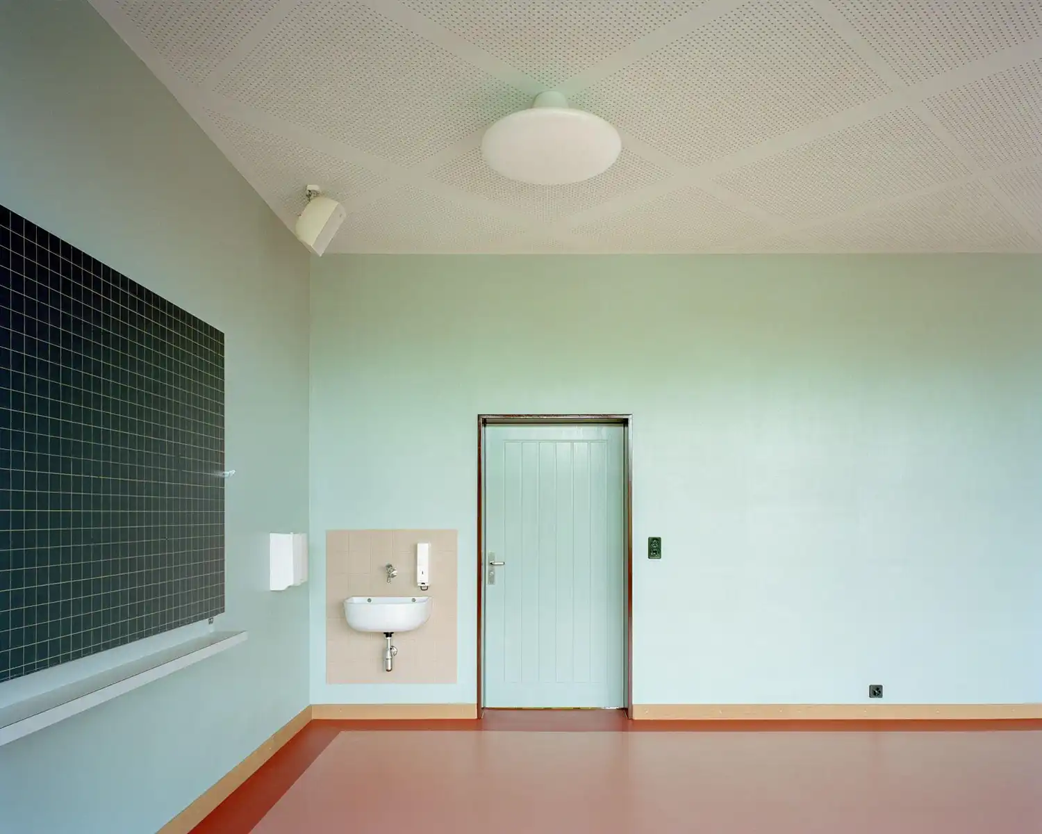 Minimalist classroom wall in mint green with custom Gellert ceiling lamp.