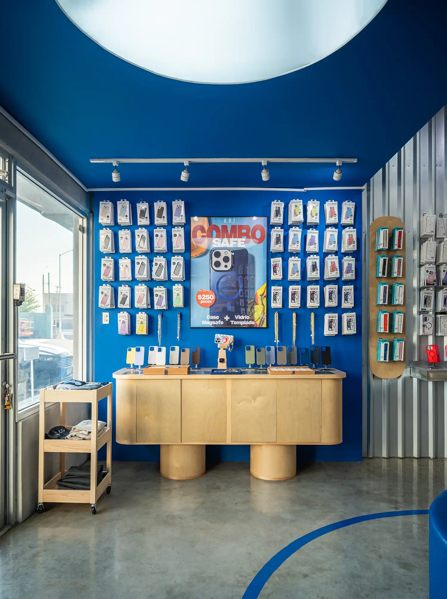 Blue wall display with smartphone accessories and birch wood cabinetry.