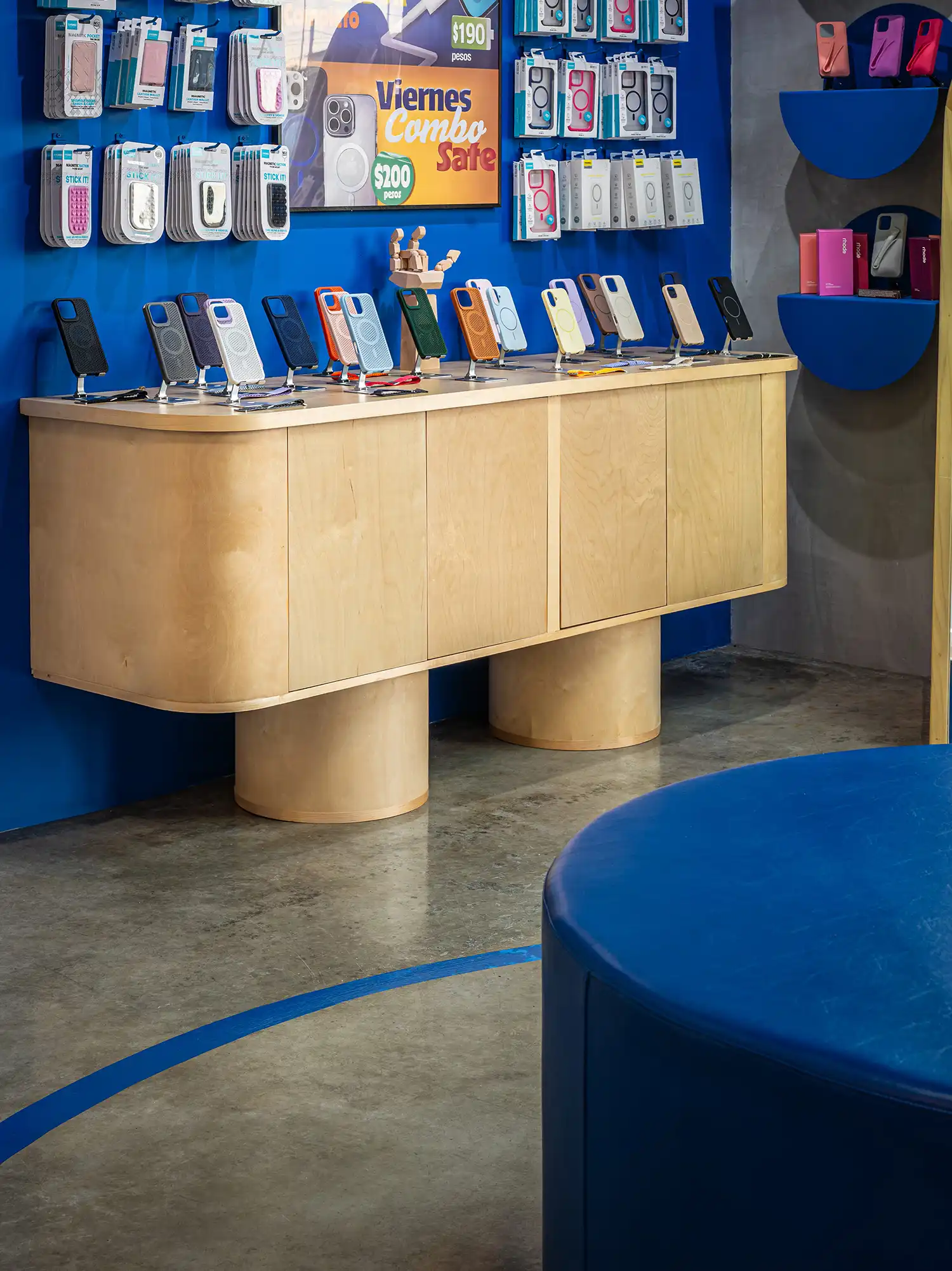 Detail of wooden display cabinet with cylindrical legs and blue wall background.