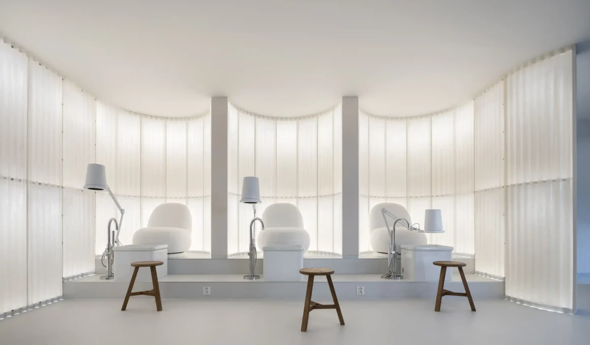A symmetrical view of three elevated white pedicure stations set against a glowing, curved fiberglass backdrop.